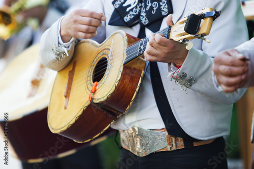 Mexican mariachi with white traditional costumes playing the vihuela at a party photo