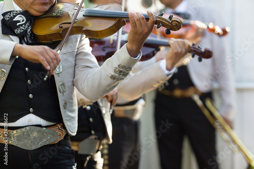 Mexican mariachi with white traditional costumes playing the violins at a party