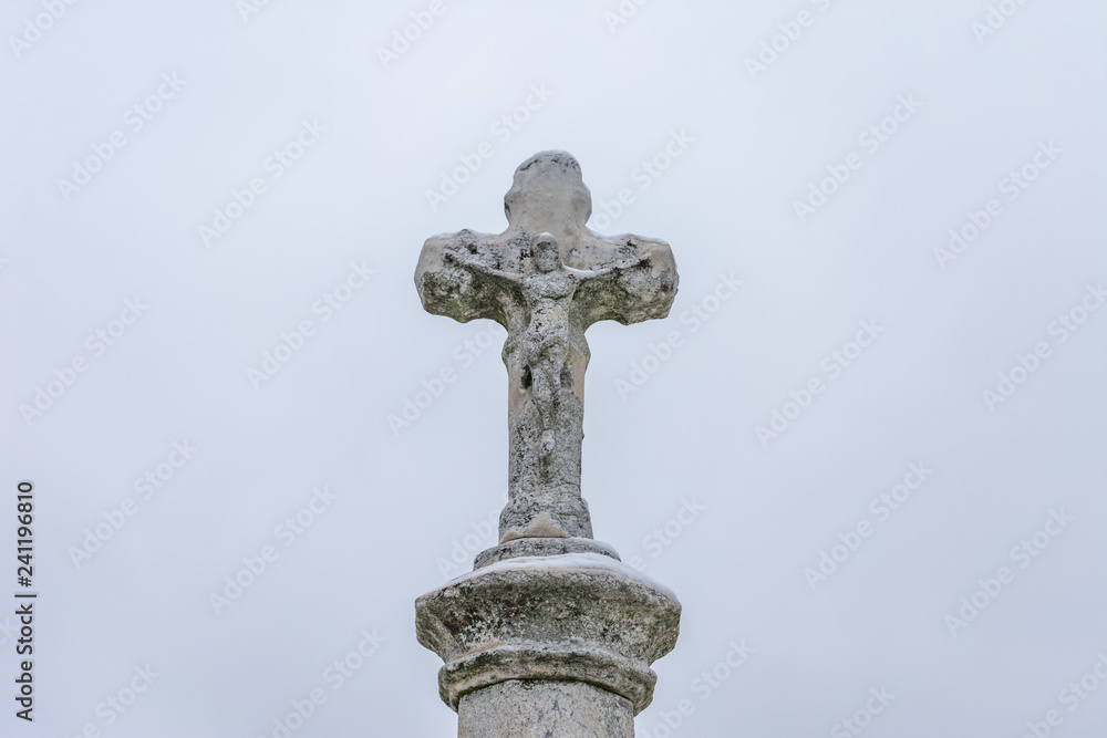 Old Stone Cross on top of a Tombstone at a Cemetery