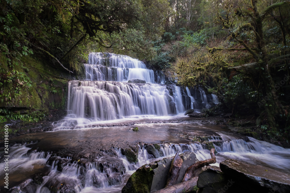 This is the Purakaunui Falls in New Zealand. A waterfall is a place where water flows over a vertical drop or a series of steep drops in the course of a stream or river. This is the Purakaunui Falls in New Zealand. A waterfall is a place where water flows over a vertical drop or a series of steep drops in the course of a stream or river.