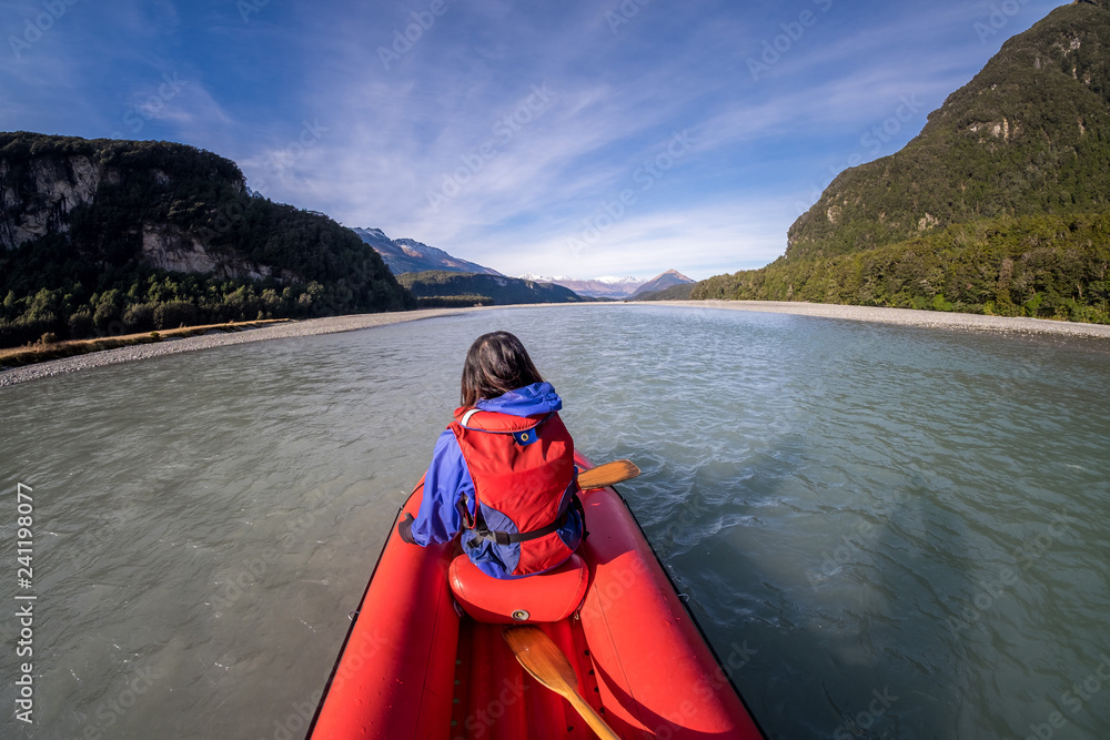 Young girl kayaking down a dart river of New Zealand. Girl traveling down river stream. Woman enjoying scenery. Lifestyle, adventure and exploration concept image. Recreation leisure activity