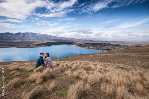 Couple enjoys beautiful scenery in New Zealand. Romantic couple smiling into the camera. A pair of couple goes on honeymoon in natural landscape. Leisure image of a young couple in happiness.