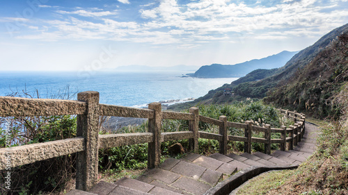 Fototapeta Naklejka Na Ścianę i Meble -  This stunning view was taken in a popular hiking track in Taiwan. The stairs lead downhills along the edge of the cliff. The scenery has mountains and ocean. Steep drop provide exciting to visitors.
