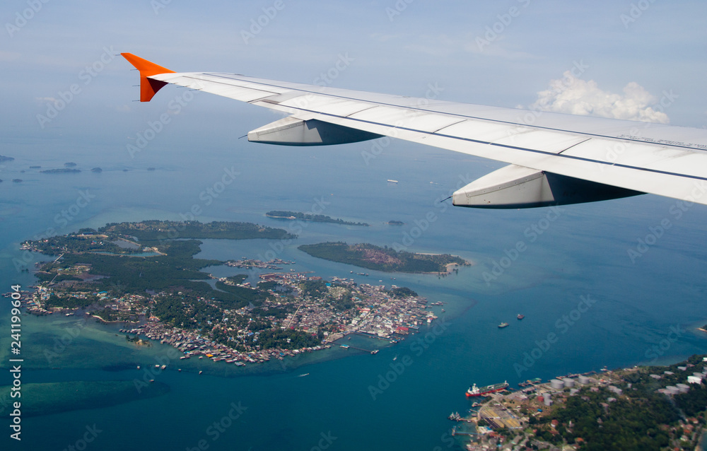 Fototapeta premium This is an aircraft wing view. The sky is deep and blue. There are amazing blue ocean below. It is very suitable for background use.