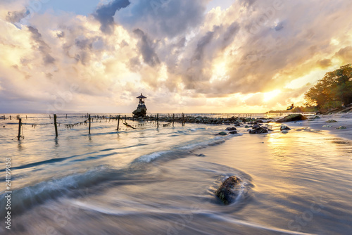 This was taken in a beach at Bali, Indonesian in Asia. It was early morning. The dawn sun brings dramatic colors in the sky and clouds. The water waves are silky and smooth.