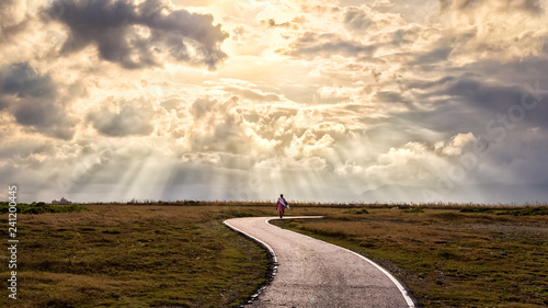 Inspirational image of person walking along path with sun rays. Suitable for background use or adding text