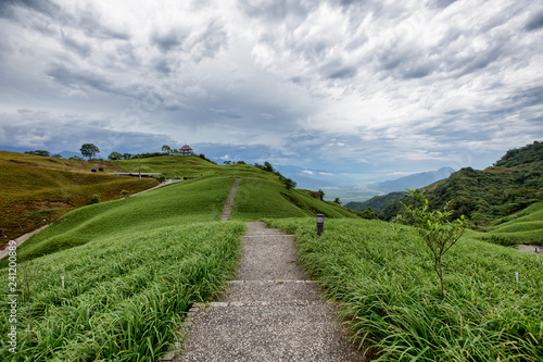 A staircase that leads into the distance. There are rolling hills here. The path goes up and down. Very interesting landscape. High on the mountains. It is a peaceful and serene landscape.