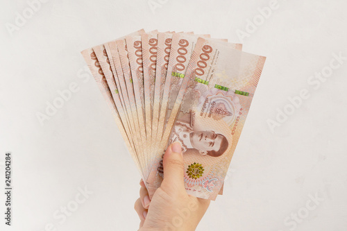 Hand holding new 1000 Thai Baht banknotes on white wall background. Business and finance concept.