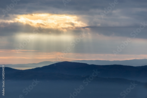 Sunray shines through clouds over the mountains and a sea of fog © Massimo