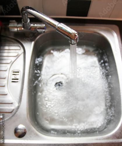 Sink full of water with running tap / faucet