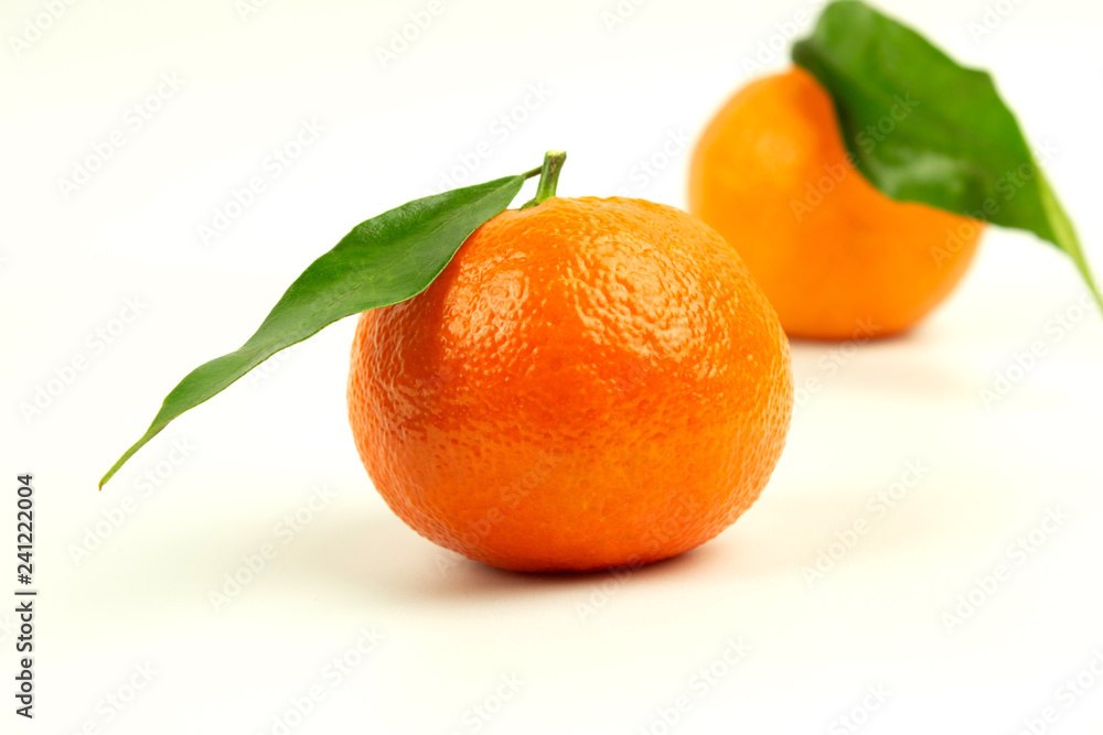 Two ripe tangerines with green leaves on a white background Two ripe tangerines with green leaves on a white background