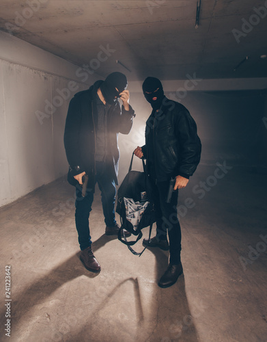 Burglars with stolen money standing in a garage after a heist