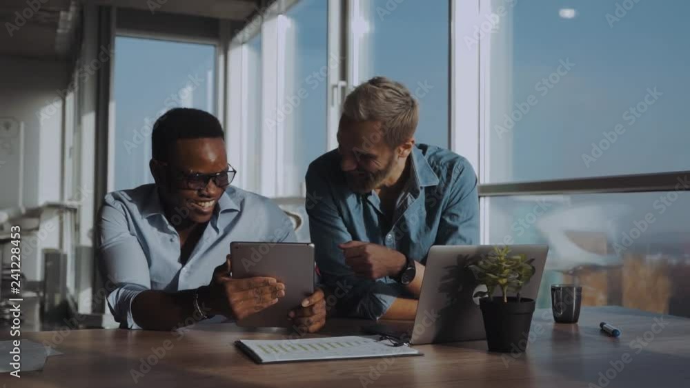 black and european men have fun with gadgets in a modern office