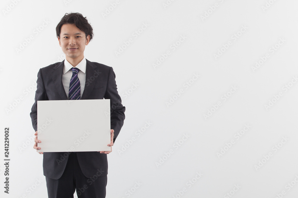 A young Asian business man holding a white board with smile A young Asian business man holding a white board with smile