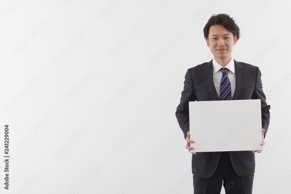 A young Asian business man holding a white board with smile A young Asian business man holding a white board with smile