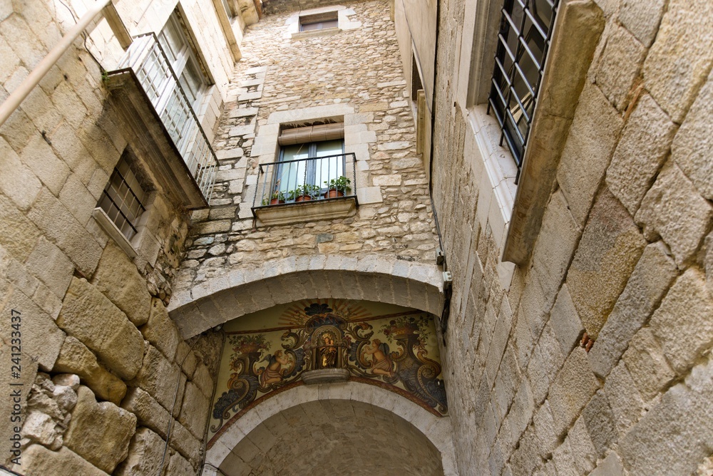 Interior view from the courtyard of a residential building in the old Girona on the house with a Catholic icon on the facade.