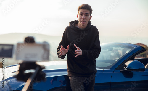 Brunette guy filming himself with camera in luxury car