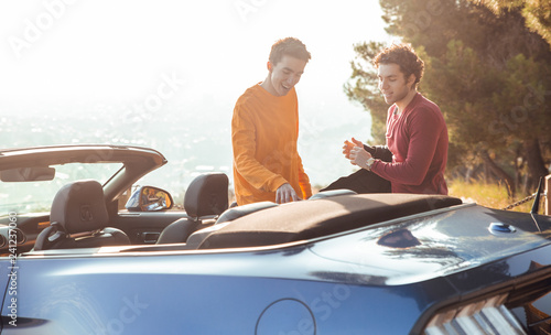 Two guys at sunrise laughing with blue car in viewpoint © Aitor