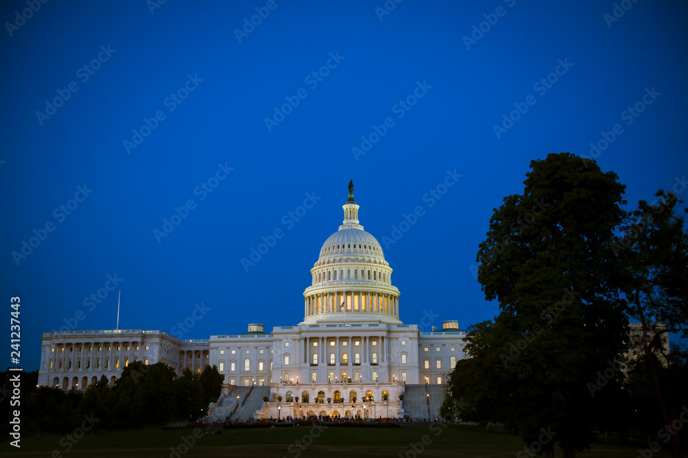 Scenic evening view of the US Capitol Building with glowing lights under blue dusk sky in Washington DC, USA