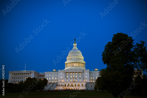 Scenic evening view of the US Capitol Building with glowing lights under blue dusk sky in Washington DC, USA