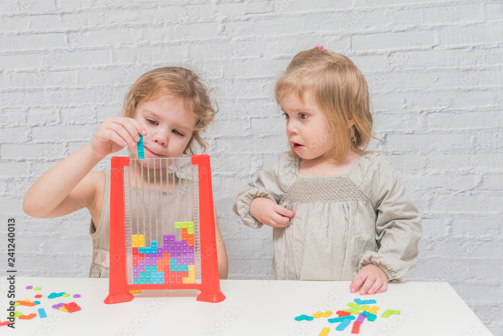 Fototapeta premium child, girl in a dress playing logic designer, on a white wall background