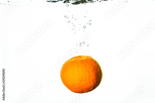 Fresh friut falls into water with splash and bubbles