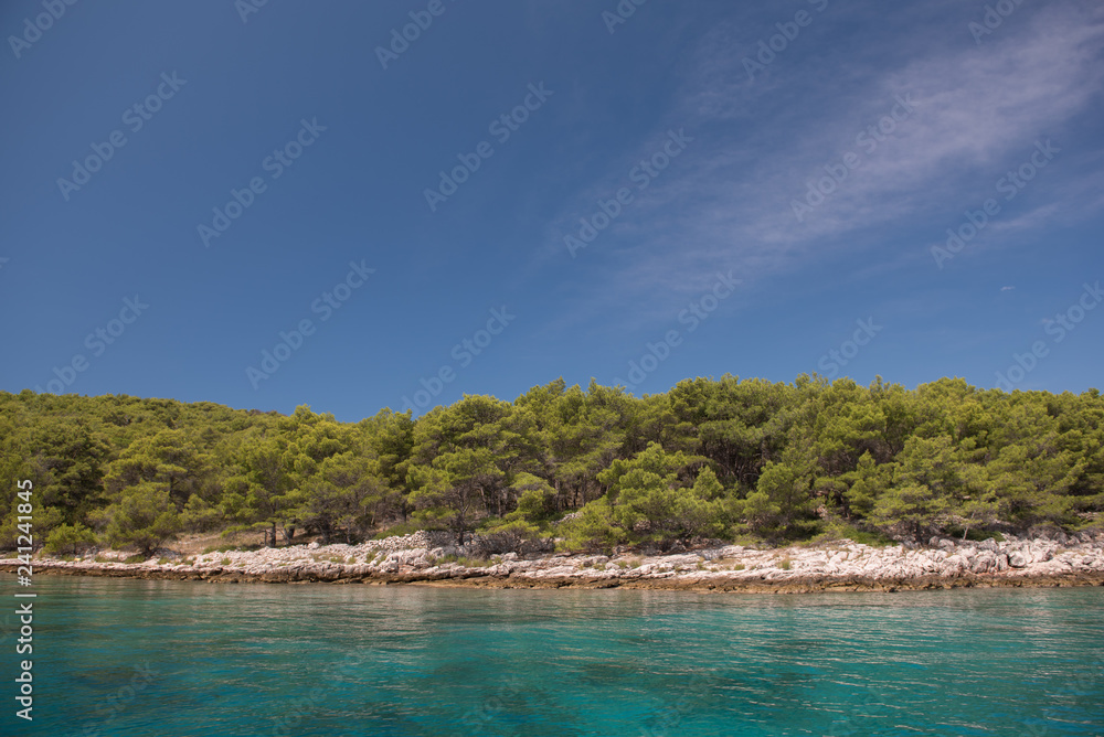 Beautiful coastline with green forest, stones and blue sky and sea water. Natural wallpaper. Adriatic coastline. Croatia. Mediterranean sea. Beautiful coastline with green forest, stones and blue sky and sea water. Natural wallpaper. Adriatic coastline. Croatia. Mediterranean sea.