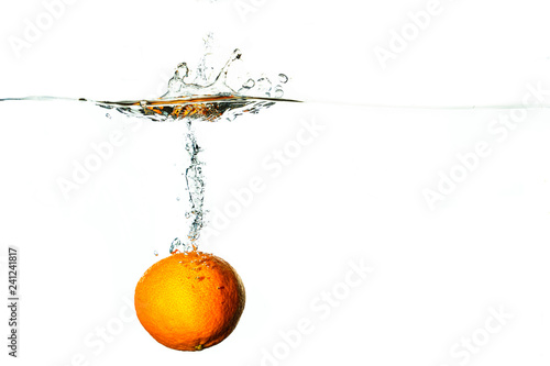 Fresh fruit dives into cold water with splash and bubbles