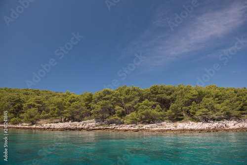 Beautiful coastline with green forest, stones and blue sky and sea water. Natural wallpaper. Adriatic coastline. Croatia. Mediterranean sea.