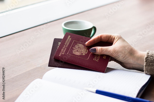 Travel, working, holiday, business concept. A woman holding a Russian passport in her hands on the background of a notebook and a blue pen. People is planning trip or vacation. Close up of woman's han