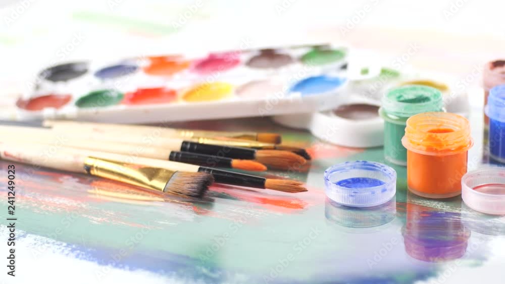 Paint brushes and watercolor paints in motion on the table Paint brushes and watercolor paints in motion on the table