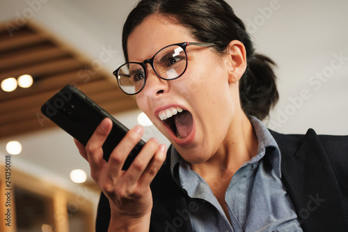 Hysterical Angry Business Woman Screaming Madly at her Smartphone photo