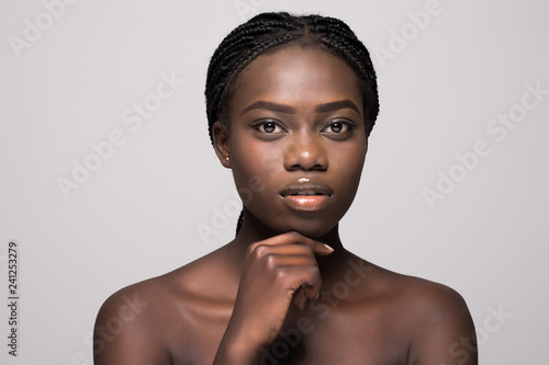 Beautiful Young african Woman with clean Fresh Skin touch own face . Facial treatment. Cosmetology, beauty and spa.