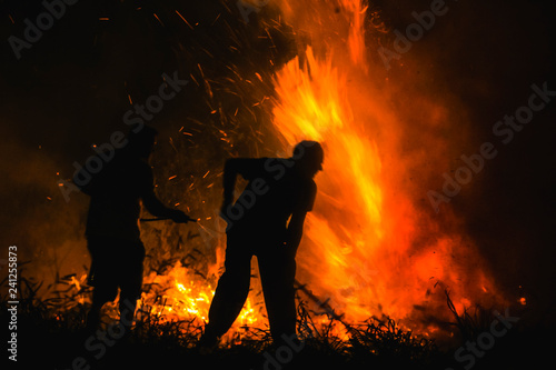 Gloria de Dourados, Mato Grosso do Sul - Brazil - August, 23, 2014. Two men try to put out a pasture fire using a damper. Silhouette photo