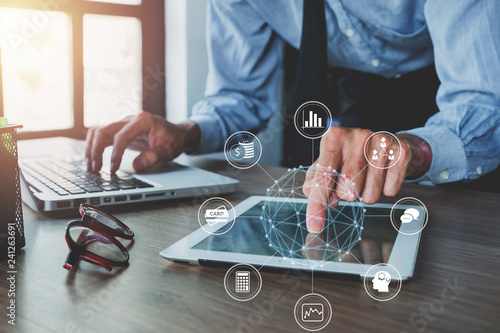 Businessman hand working with digital tablet and modern computer with VR icon diagram at office.Digital marketing media in virtual screen. photo