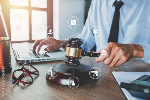 Tapet Male judge working with laptop computer, legal books and gavel on white wooden table in courtroom