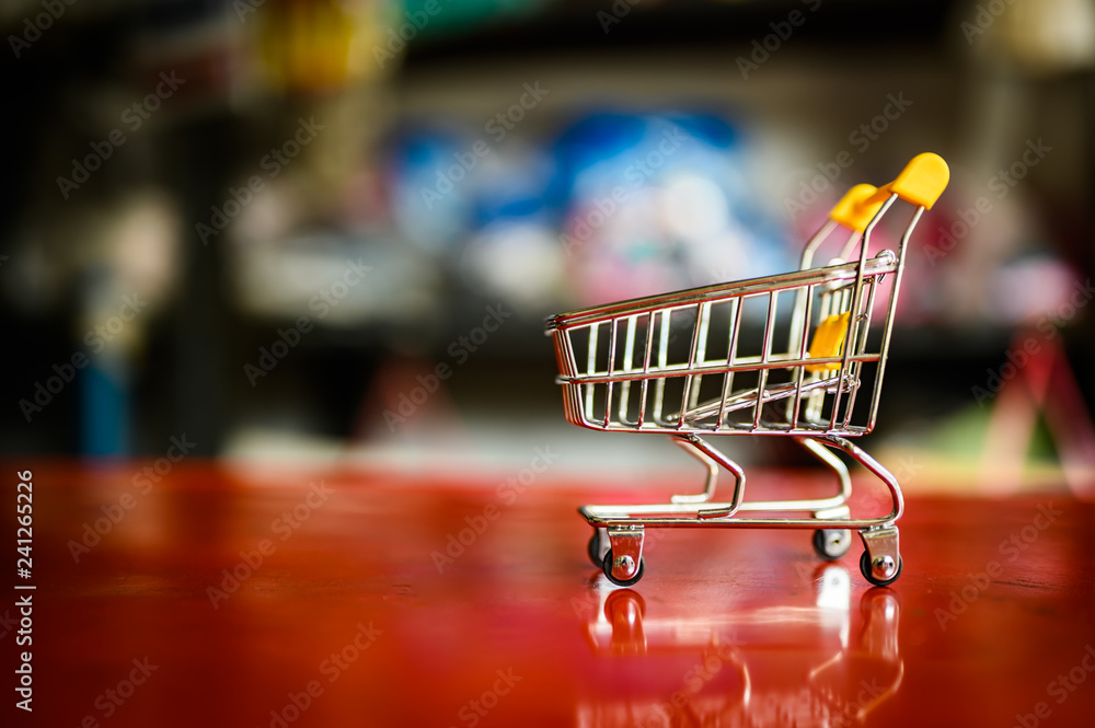 empty yellow shopping cart with supermarket blur abstract background.