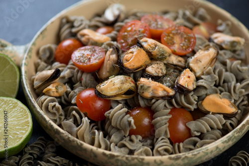 Close-up of fusilli made of hemp flour and served with tomatoes and mussels, studio shot