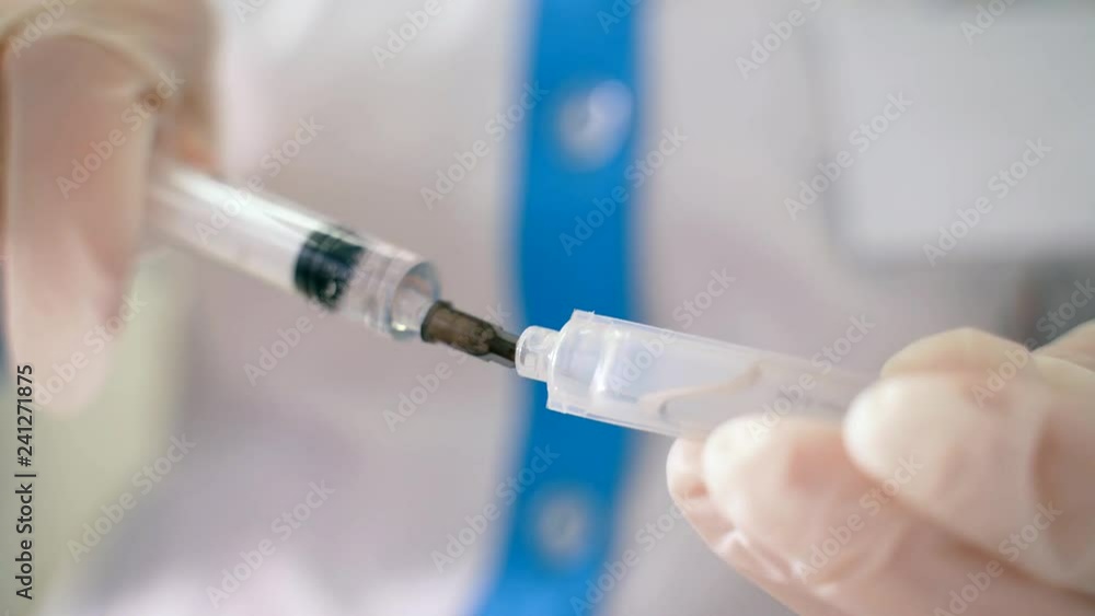 health worker dials the vaccine into a syringe. health worker dials the vaccine into a syringe.