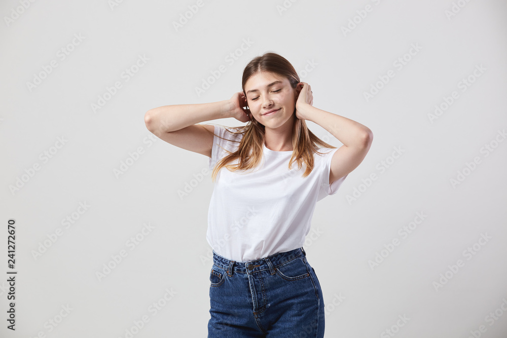 Lazy girl dressed in a white t-shirt and jeans is on a white background in the studio Lazy girl dressed in a white t-shirt and jeans is on a white background in the studio