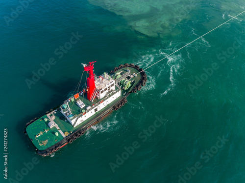 Aerial view Tug boat draging container ship in the sea for logistics import export, shipping  or transportation. © Pawinee