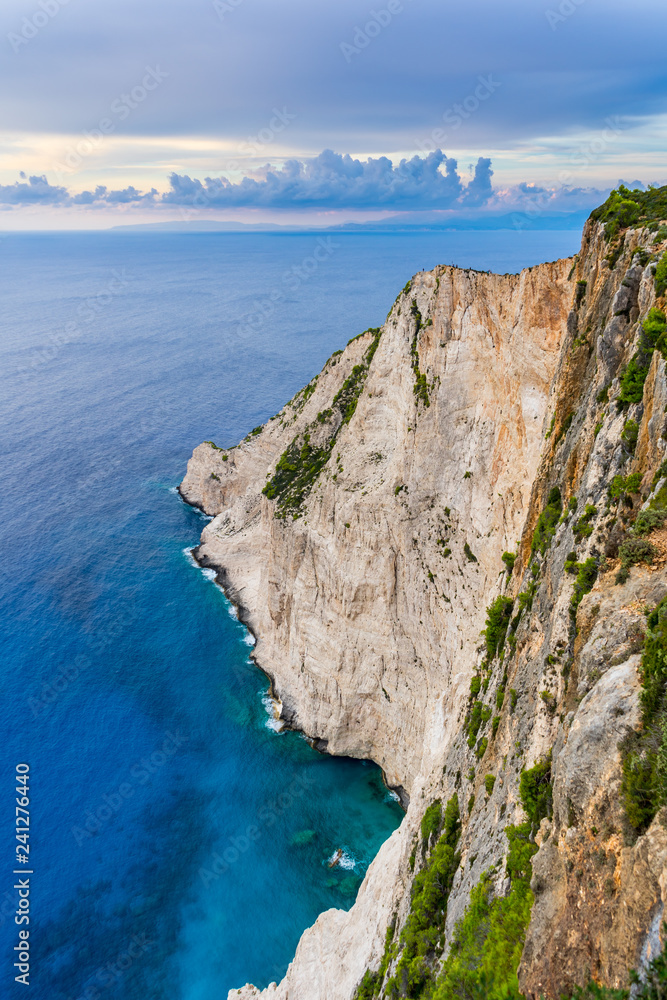 Fototapeta premium Greece, Zakynthos, Abrupt massive rock wall cliff in azure waters at navagio beach