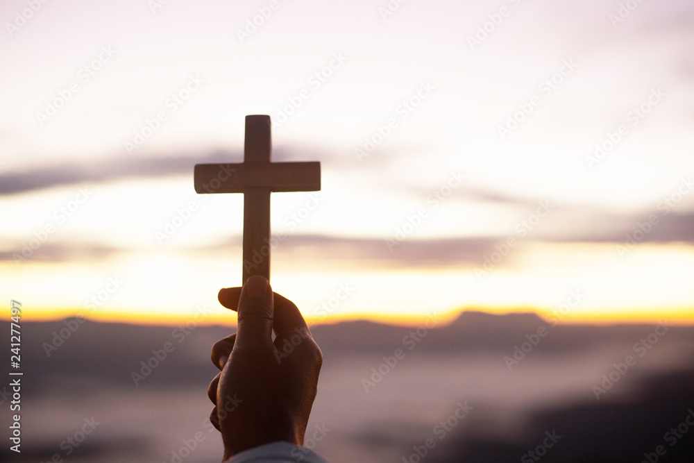 Hands holding wooden cross  on sunrise background, Crucifix, Symbol of Faith.