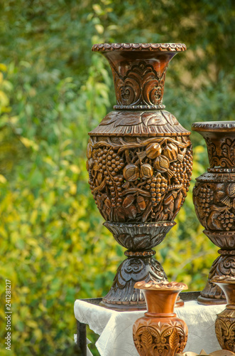 Bright polished wooden vase with a carved in traditional ethnic style with a pattern of grapes and pomegranate on the branches with leaves