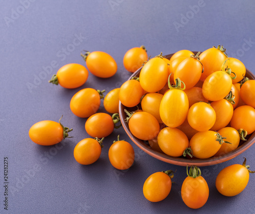 Fresh cherry tomatoes in a wooden bowl isolated on a blue background, close up, copy space photo