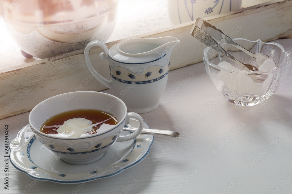 East frisian tea time. Cup of hot tea served on a wodden table. East frisian tea time. Cup of hot tea served on a wodden table.