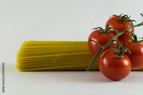 Spaghetti and fresh tomatos on white background. Delicious italian cusine. Creative background for food or cooking concept.