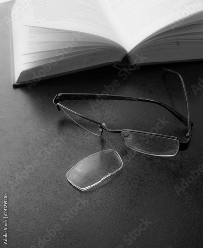 Black and White image of eyeglasses break on blur book background,