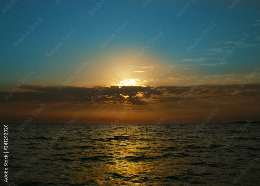 Naklejka premium Blue summer sky and bright orange sea sunset in the clouds