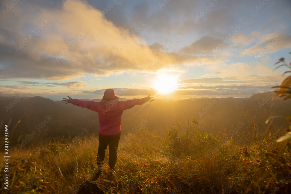 rear of happy woman stand on top mountain looking view with sunrise and mist at Doi Langka Luang, Chiang Rai province. soft focus.